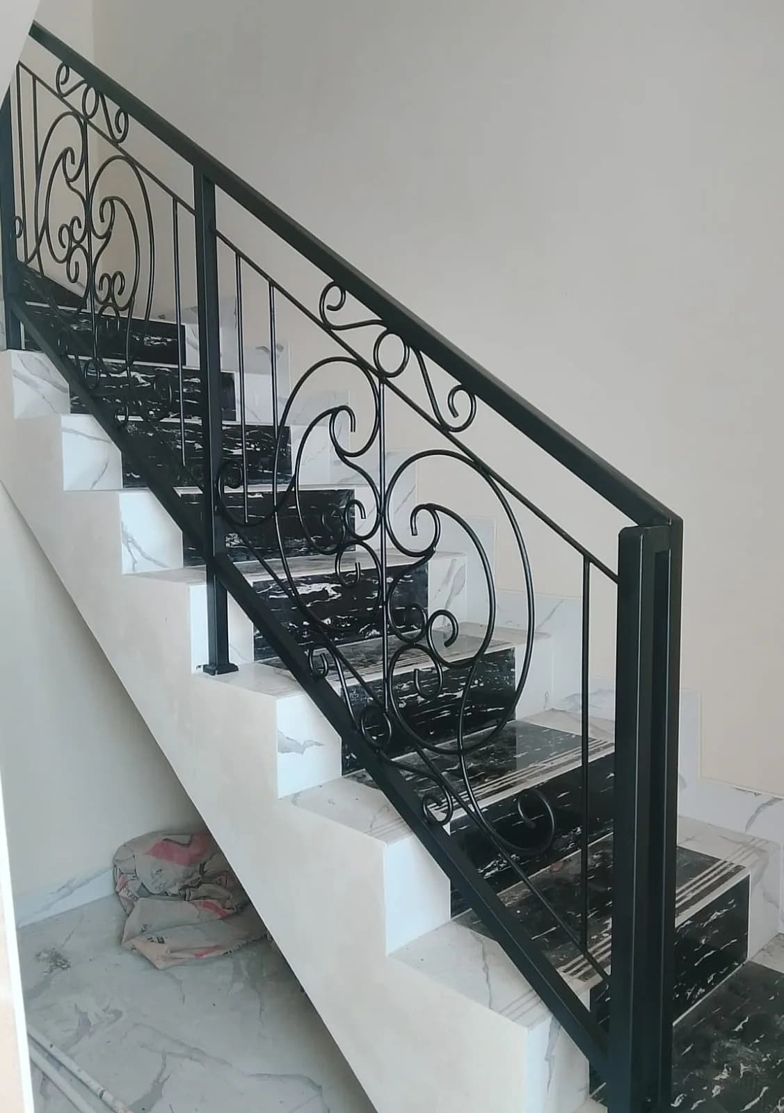 Railing tangga besi hijau tua motif scroll pada tangga marmer